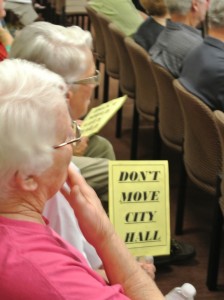Holding a sign opposing moving city hall, resident Susan Miller awaits a decision from the council, Thursday night.