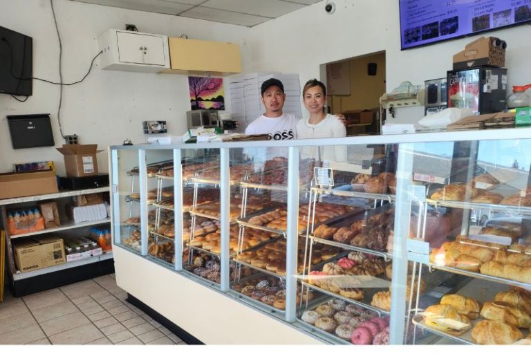 New owners of Master Donuts, Bee and Long Keo stand behind a counter of pastries inside the shop. // SB Williams