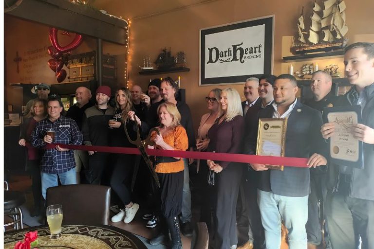 DarkHeart Brewing owners Rick and Cynthia Lee stand behind a ribbon along with city staff, Citrus Heights Chamber of Commerce Executive Director Sheri Merrick, and representatives from the offices of Sacramento County, State Assembly and State Senate.