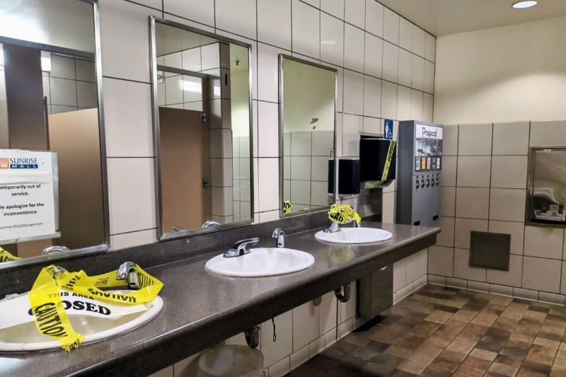 Women's restrooms in Sunrise Mall's abandoned food court with 2 sinks taped off with yellow caution tape. // SB Williams